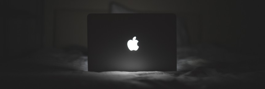 dark bedroom with macbook lit-up mac logo